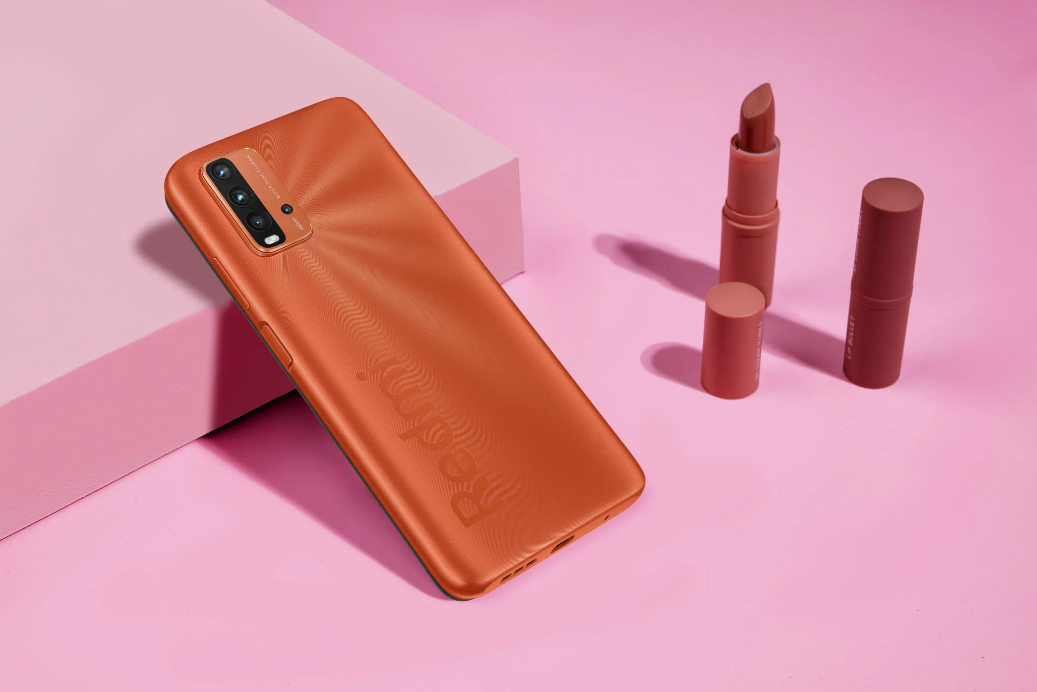 Product photograph of a red phone and two lipstick.